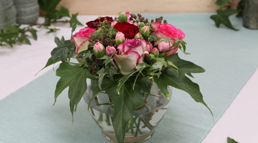 Rosengesteck mit Nelken und Efeu im Glas mit Löcherdeckel