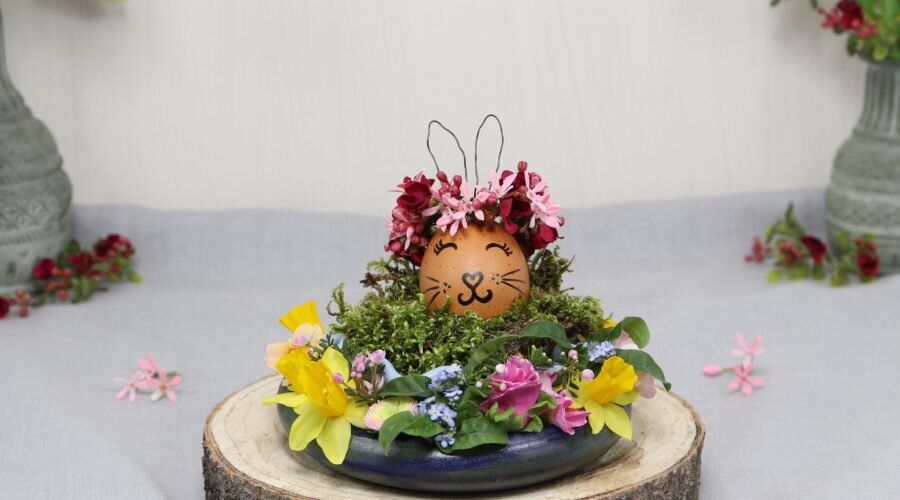 Osterdeko: Osterei mit Hasenohren und Blumenring